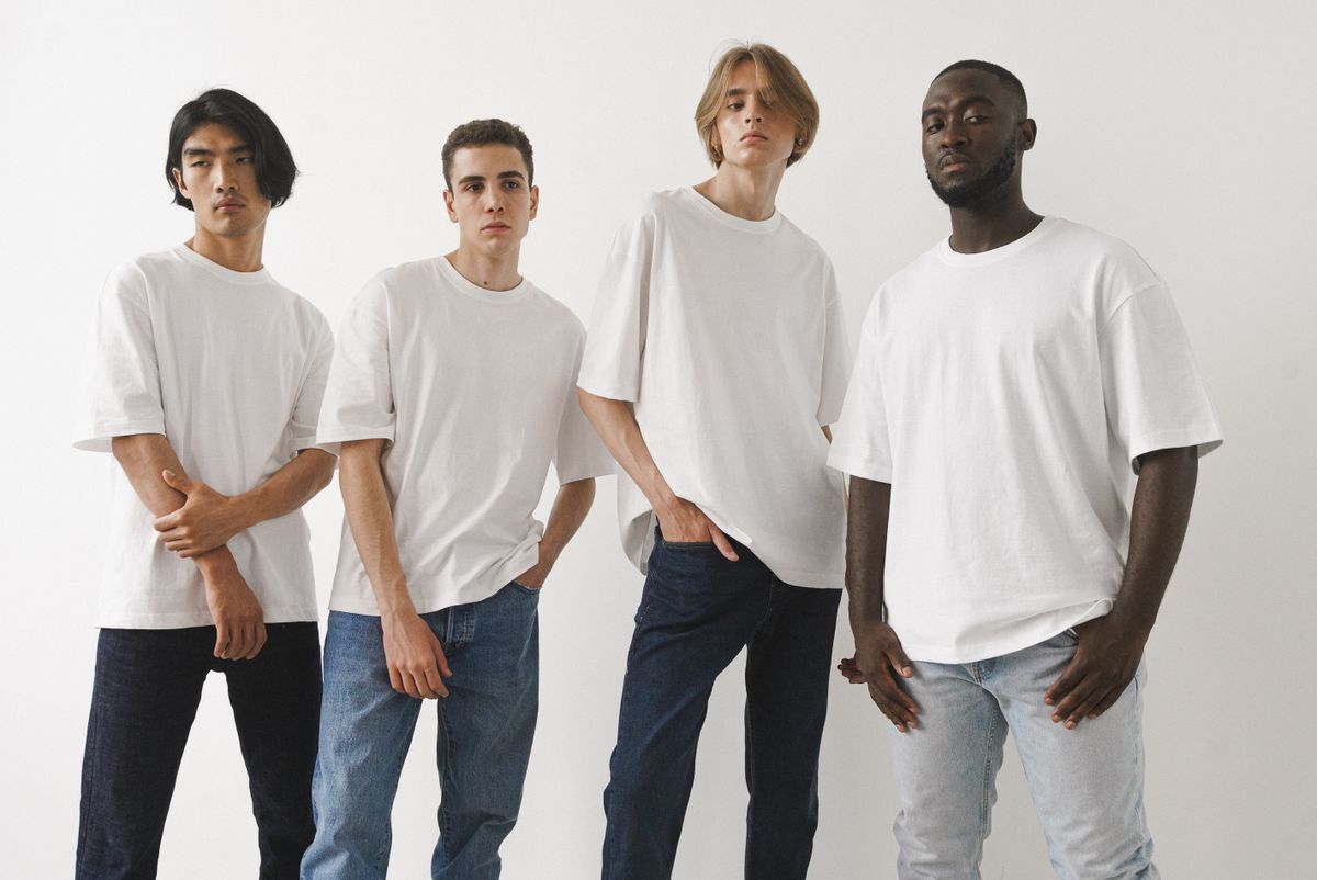 Vier jonge mannen in effen witte T-shirts tegen een lichte achtergrond