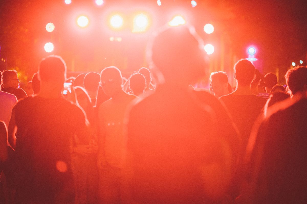 Publiek voor een festivalpodium in rood tegenlicht
