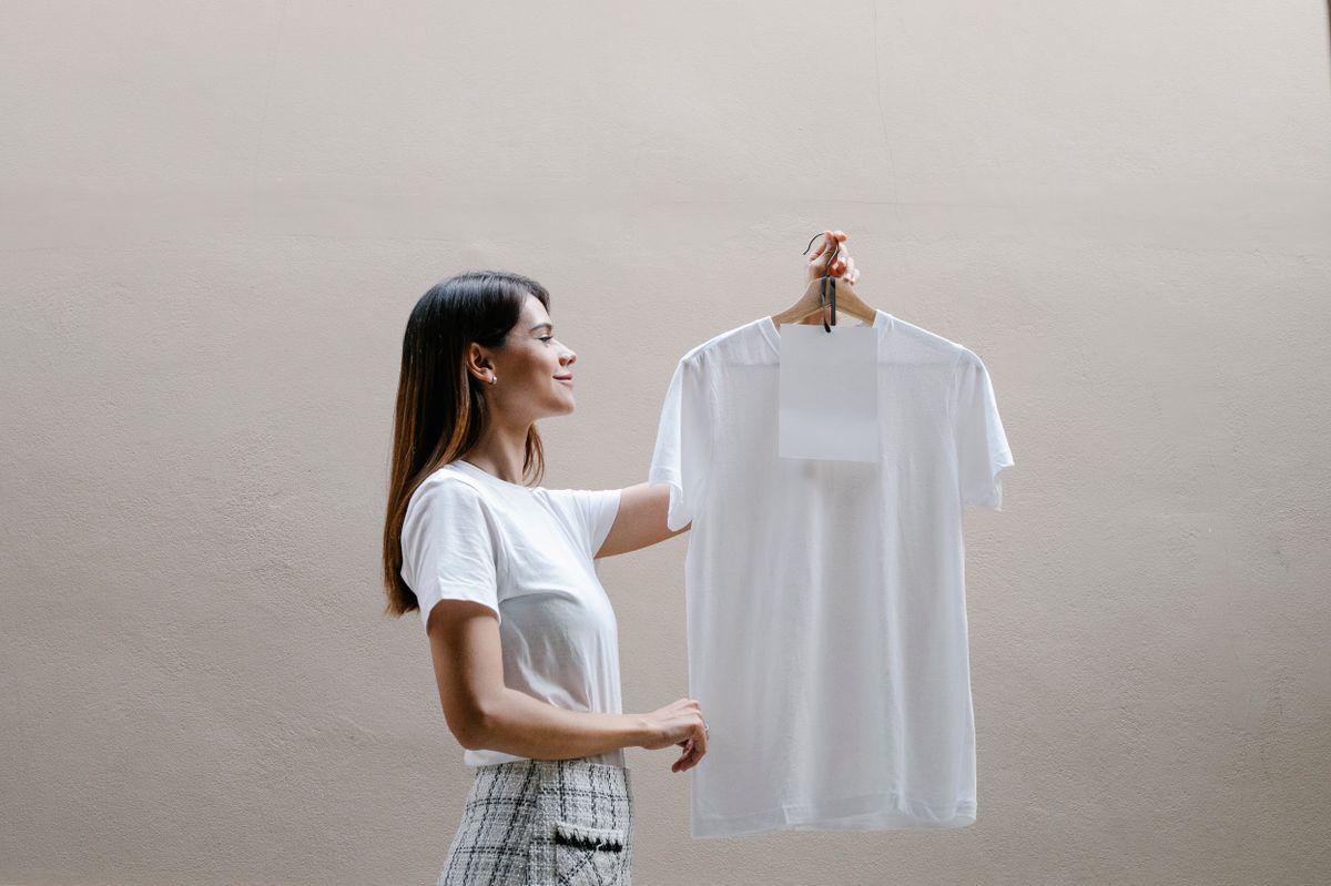 Vrouw houdt een blanco wit T-shirt aan een hanger omhoog