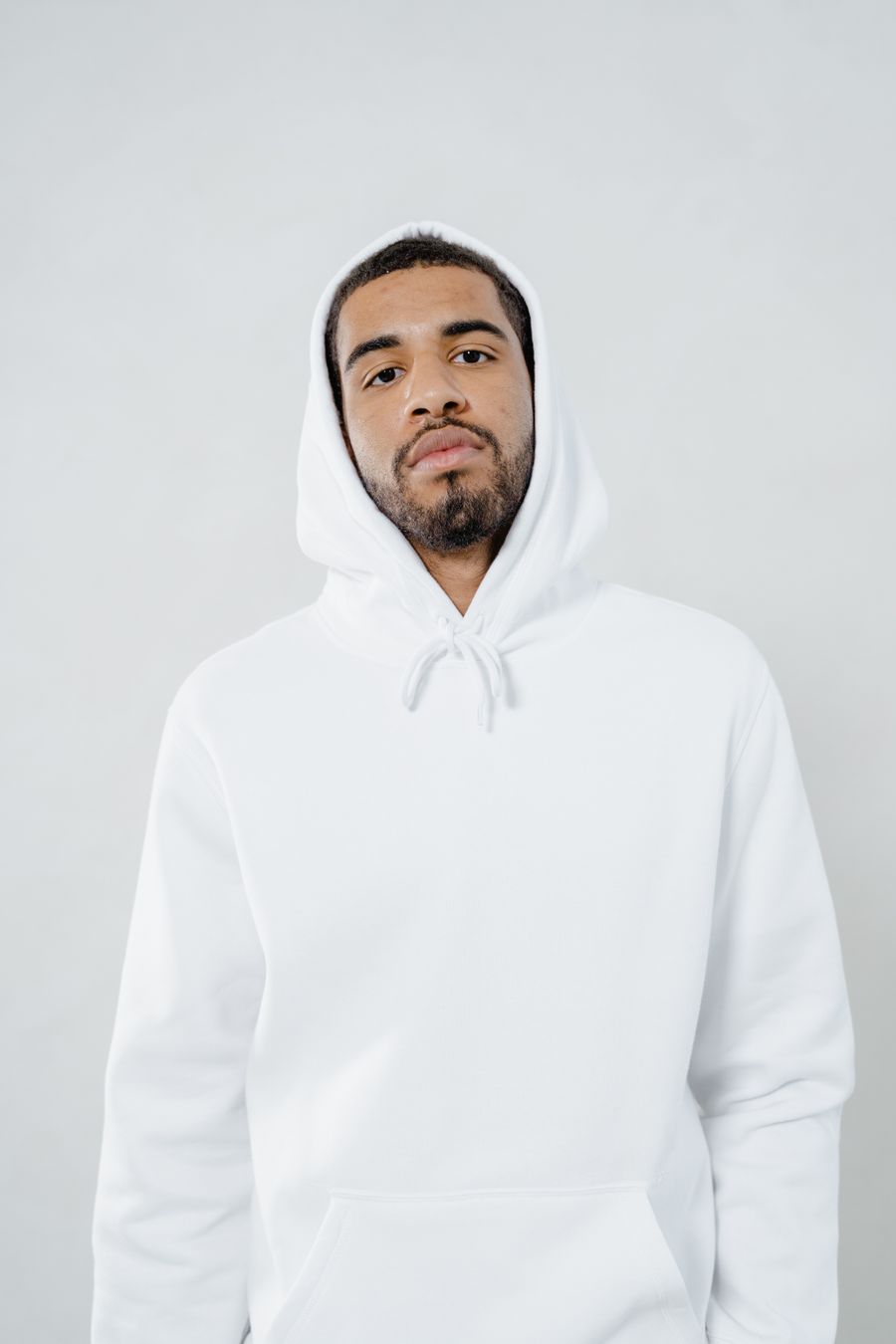 Persoon in een witte hoodie zonder opdruk, vooraanzicht tegen een witte achtergrond