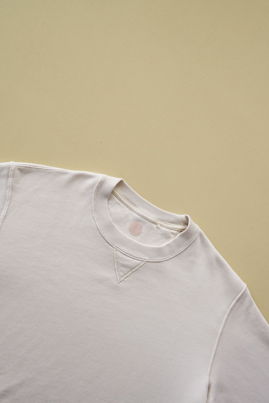 Witte sweater zonder opdruk tegen een cremekleurige achtergrond